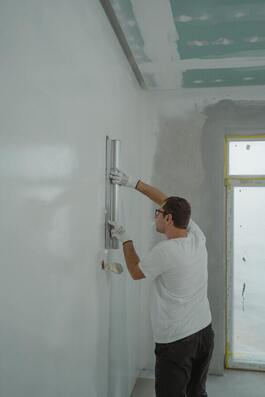 A worker applying concrete to a vertical surface